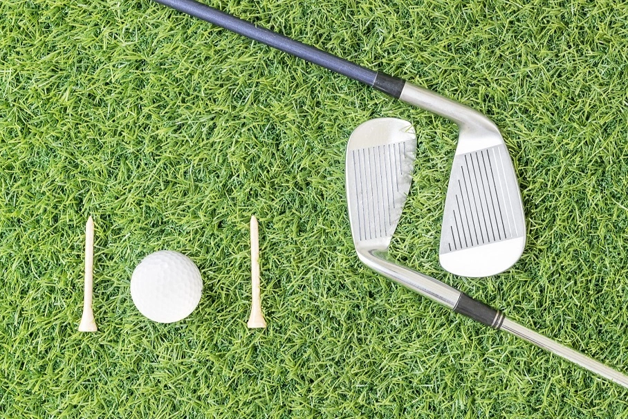 Two golf clubs lying on the grass, positioned parallel on the course.