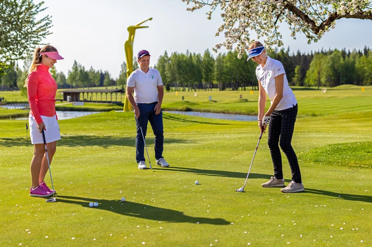 Large group of golfers standing together on the course, dressed in golf attire.