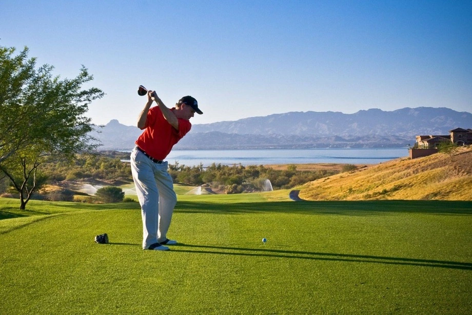 Man swinging a golf club on the course, focusing on his shot.